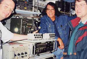 Three people seated near electronic laboratory equipment