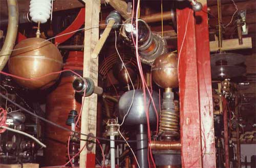Dense Hutchison lab equipment with copper coils, spheres, and high-voltage components